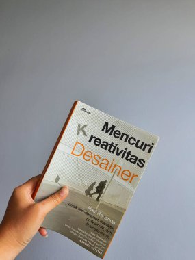 A hand is holding a book, with the title: Stealing Designer Creativity.