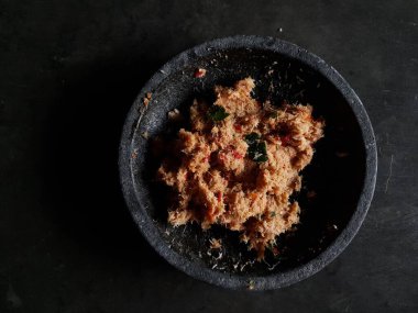 Grated coconut is mixed with spices consisting of garlic, chili, sugar, palm sugar, salt and lime leaves. The taste is spicy and savory with a little sweetness, very good when mixed with vegetables. Very suitable for dieting. In this photo, grated co