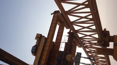 Vertically frame video. This is the steel structure of a launcher gantry that will be used for erection precast concrete I Girder across the river . This yellow gantry launcher comes from China with a capacity of up to 140 tons.
