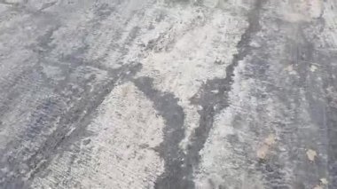 Vertically frame video. Point of view of a person walking face down, where the unfinished asphalt road is visible.
