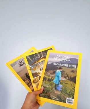 West Java in August 2022. A hand holds the Indonesian version of the National Geographic magazine. National Geographic is the official journal of the National Geographic Society which has provided information about the world and all its contents glob