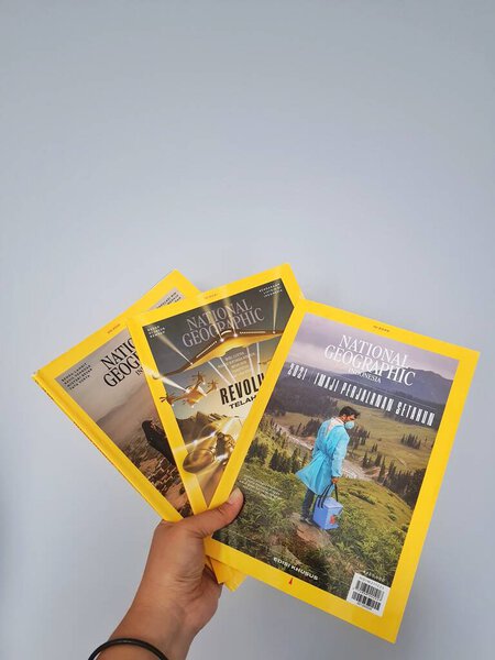 Западная Ява в августе 2022 года. Рука держит индонезийскую версию журнала National Geographic. National Geographic - официальный журнал Национального географического общества, который предоставил информацию о мире и его содержании