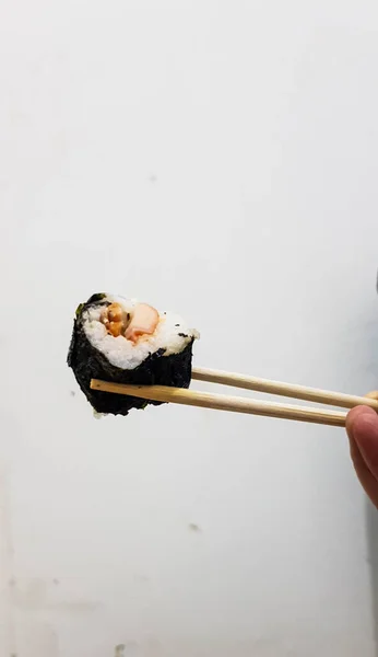 Trozo Sushi Sostenido Con Palillos Con Fondo Pared Blanco —  Fotos de Stock