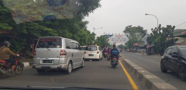Nisan 2019 'da Batı Cava. Atardamar tıkanıklığında motosiklet ve arabaların arka görüntüsü. Trafik sıkıştığında, araç yavaş çalışır ve hatta geçici olarak durur..