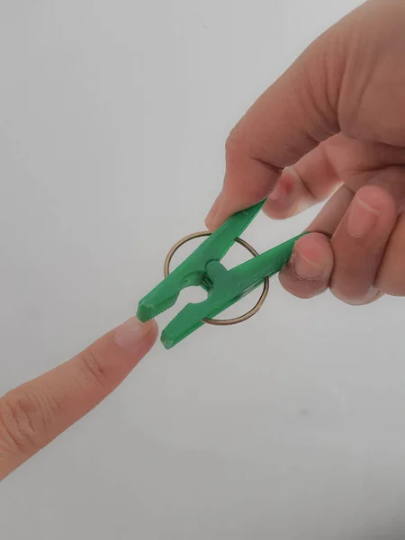 Egy Kéz Megpróbálja Megcsípni Hüvelykujját Egy Zöld Ruhatűvel Elszigetelt Fénykép — Stock Fotó