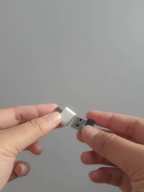 Cakarta, Endonezya Temmuz 2021. Bir el, Adapter USB USB tip C 'ye küçük bir matara diski Gri beyaz arkaplandaki OTG adaptör OTG kablo dönüştürücülerine yerleştirmeye çalışıyor..