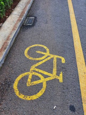 Endonezya 'daki asfalt yolda sarı çizgili bisiklet yolu tabelası. Sürücüler dönmeden ya da park etmeden geçmemeli ve önce motorlara teslim olmamalısın..