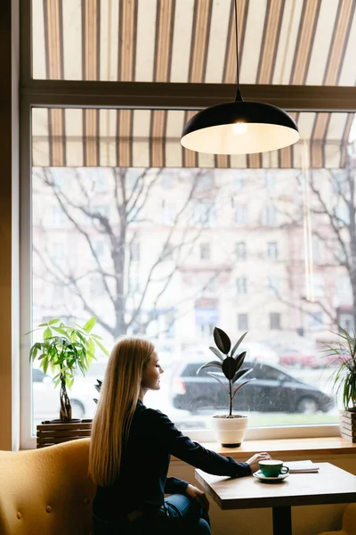 Girl sitting in a cafe near the window with a cup of coffee