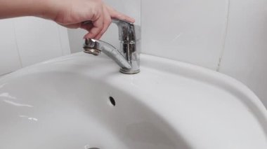 Eller su musluğunu açar.