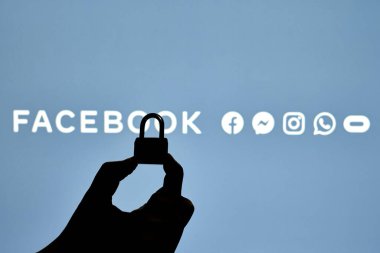 Taşkent, Özbekistan - 7 Ekim 2021: Facebook logosu üzerinde asma kilit tutan bir kişinin silueti. Facebook bloğu, kısıtlama veya sansür kavramları. Facebook kesintisinin sembolü
