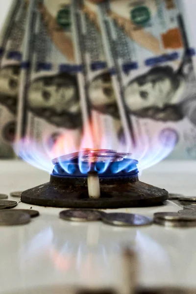 Burning gas stove burner and US dollar banknotes. Pay for natural gas, gas bill, tariff. Pile of coins and burning fire gas stove hob and money