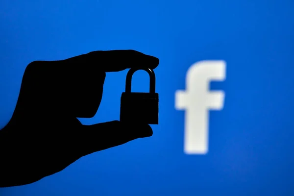 Taşkent, Özbekistan - 7 Ekim 2021: Facebook logosu üzerinde asma kilit tutan bir kişinin silueti. Facebook bloğu, kısıtlama veya sansür kavramları. Facebook kesintisinin sembolü