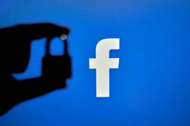 Taşkent, Özbekistan - 7 Ekim 2021: Facebook logosu üzerinde asma kilit tutan bir kişinin silueti. Facebook bloğu, kısıtlama veya sansür kavramları. Facebook kesintisinin sembolü