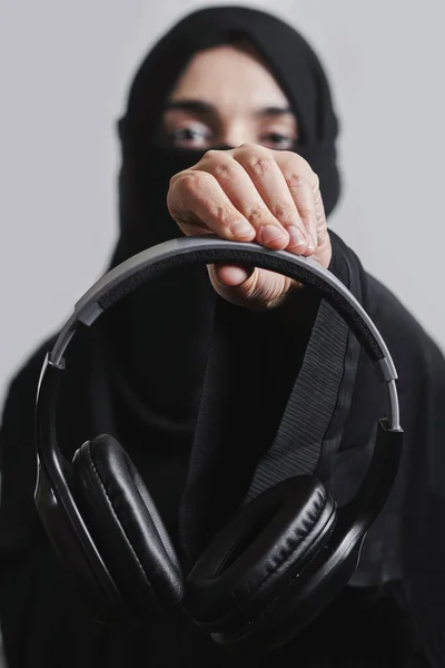 Mulher muçulmana no hijab detém fones de ouvido — Fotografia de Stock