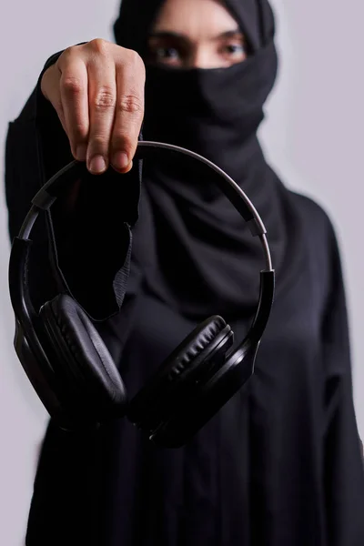 Muslim woman in hijab holds headphones — Stock Photo, Image
