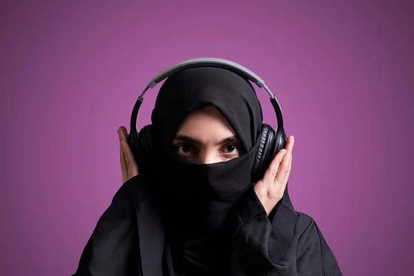 Мусульманка в Хіджабі слухає музику з бездротовим заголовком. — стокове фото