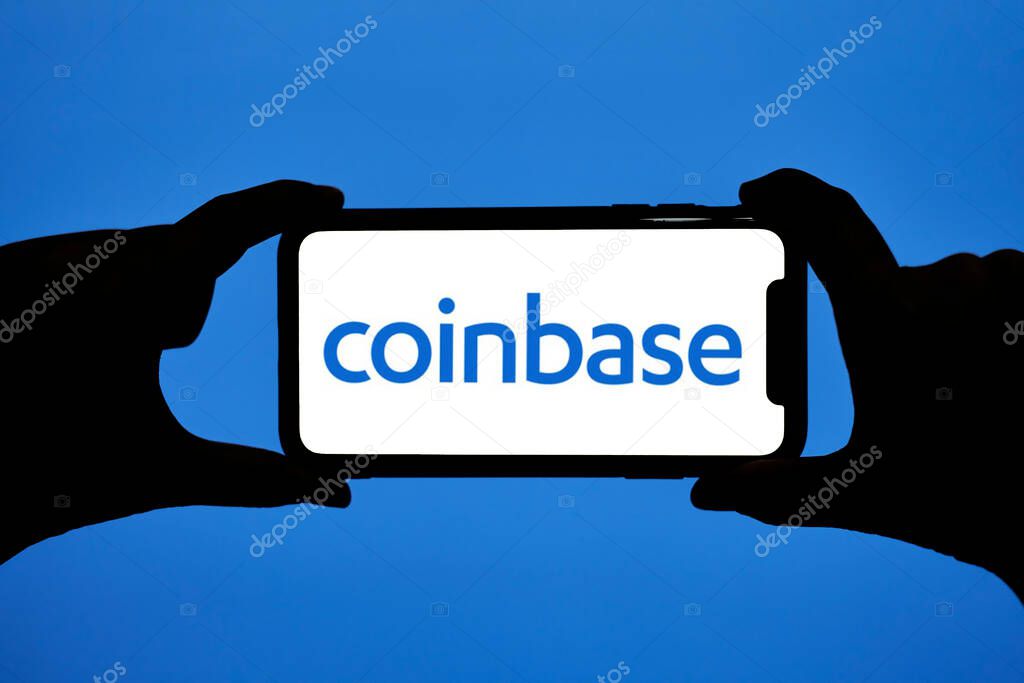 Tashkent, Uzbekistan - 22 October, 2021: Hands hold smartphone with Coinbase logo. Close-up of mobile phone screen with logo lettering Coinbase trading platform