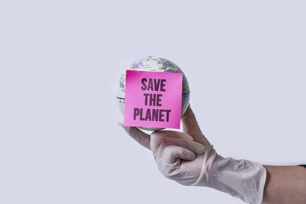 Hand in medical gloves holds a globe with note - save the planet — Stock Photo, Image