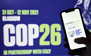 Elinde COP26 logosu olan bir telefon var.