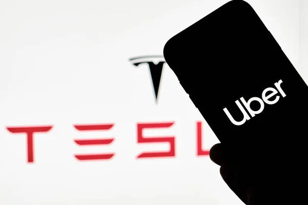 A person holds smartphone with Uber trademark with Tesla logo — Stock Photo, Image