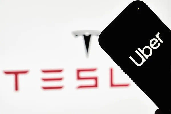 A person holds smartphone with Uber trademark with Tesla logo — Stock Photo, Image