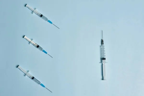 Syringes on bright blue. Symbol of three Covid-19 booster shot — Stock Photo, Image