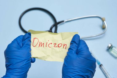 Doktor eli Omicron metniyle buruşmuş bir kağıt parçası tutuyor.