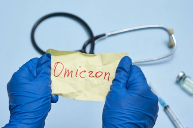 Doctor hand holds a piece of rumpled paper with Omicron text clipart