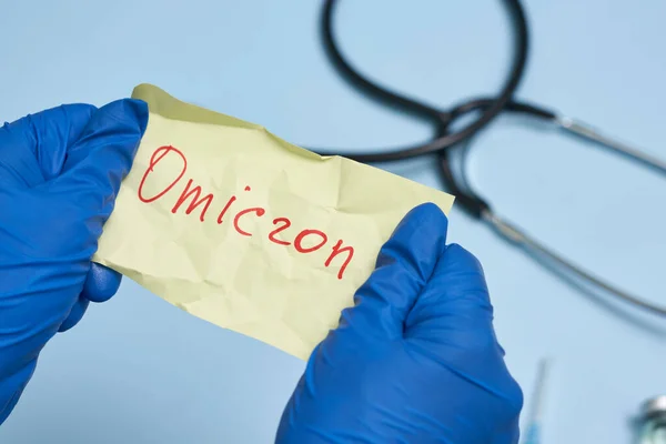 Dokter hand houdt een stuk gerimpeld papier met Omicron tekst — Stockfoto