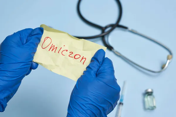 Dokter hand houdt een stuk gerimpeld papier met Omicron tekst — Stockfoto