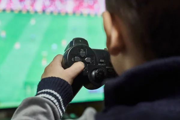 Um menino jogando futebol em uma consola de jogos — Fotografia de Stock