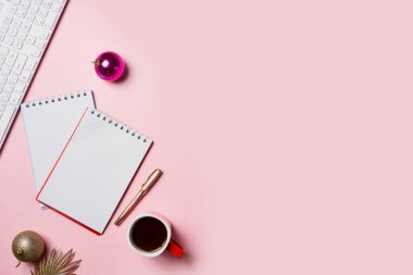 Noel süslemeleri, kahve fincanı ve pembe defter içeren ofis masası. Düz yerde, üst tarafta. Noel çalışma alanı.