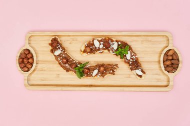 Tahta tabakta fıstık ezmeli, badem ve fındıklı muz. Sağlıklı yiyecekler. Kapat.