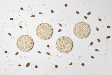 Beyaz arka planda bir yığın pirinç keki, yulaf ezmesi ve fındık. Sağlıklı atıştırmalıklar