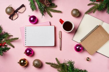 Yılbaşı ofis masasında defter, bir fincan kahve, noel altını ve pembe süslemeler. Düz yatıyordu. Metin için boşluk olan üst görünüm.