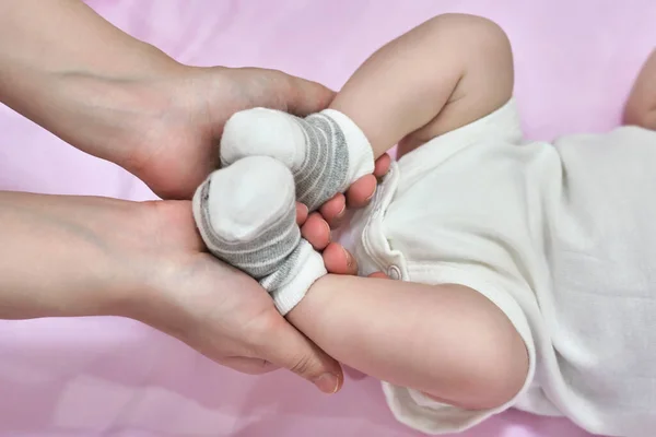 女性置く上の靴下とルーマーのために赤ちゃん作る足マッサージへ彼女の小さな子供閉じるアップ — ストック写真