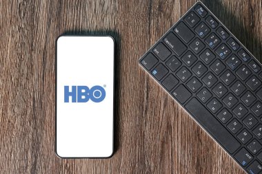 Miami, ABD - 03.26.2021: HBO Max uygulaması ahşap arka plandaki akıllı telefon ekranında ve yanında bir bilgisayarla. Filmler ve TV dizileri için canlı yayın uygulaması