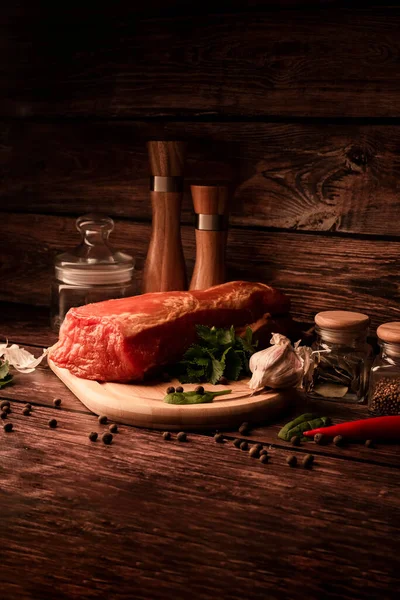 Meat on a wooden table with addition of fresh herbs and aromatic spices. Natural product from organic farm, produced by traditional methods