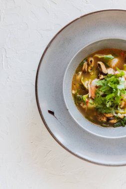 Bok, soğan ve gyoza soslu deniz mahsulü çorbası. Beyaz arka plan. Gri tabak