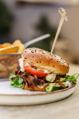 Çizburgerin yanında patates kızartması, tahta tahtada uzanmış, domates.