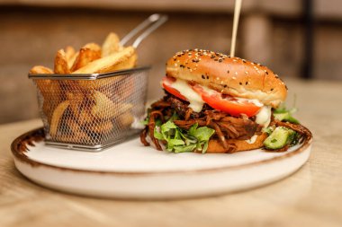 Çizburgerin yanında patates kızartması, tahta tahtada uzanmış, domates.