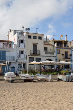 Blanes, Katalonya, İspanya -4 Ağustos 2022: Kosta Brava 'nın kıyı kasabasındaki evler, önünde balıkçı tekneleri ve İspanya' da dalgalanan Katalonya bayrağı.