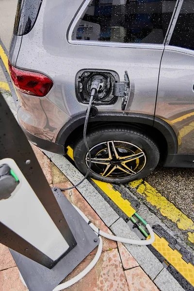 Electric car on a rainy day connected. Concept of replacing fossil fuels as an energy source in traditional CO2 emitting vehicles.