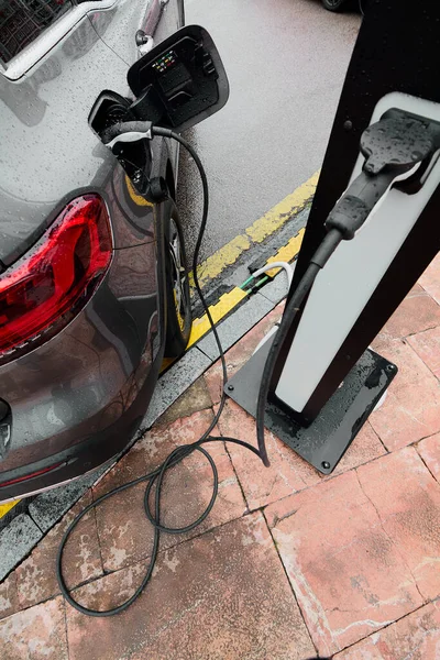 Electric car on a rainy day connected to charging cable