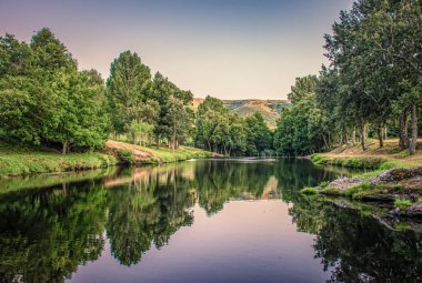 Natural pool next to the Tuela river in Hermisende (Zamora - Spain), reflecting the forest on the river. sanabria