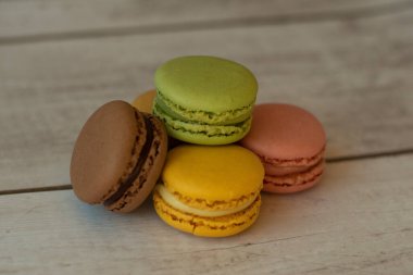 colored macaroons on aged white wooden background.