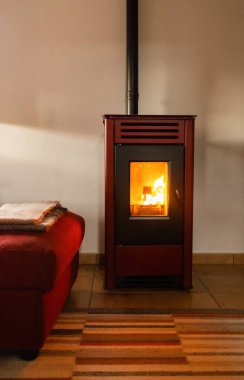 Rahat bir oturma odası, bir kanepesi, bir halısı ve yanan kırmızı bir ocağı var..