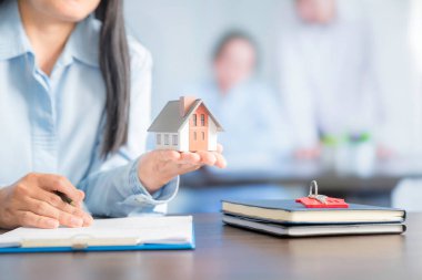 Businesswoman choosing mini house model from model on wood table, Planning to buy property. concept of Choose the best.
