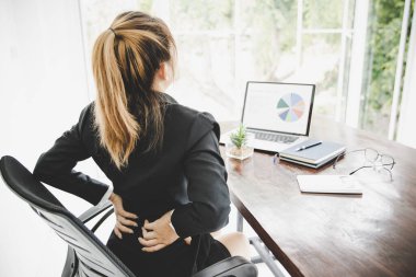 Young business woman at the office with terrible back pain while she is working in the office .Health problems concept
