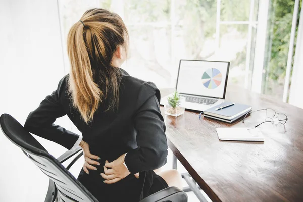 Young business woman at the office with terrible back pain while she is working in the office .Health problems concept